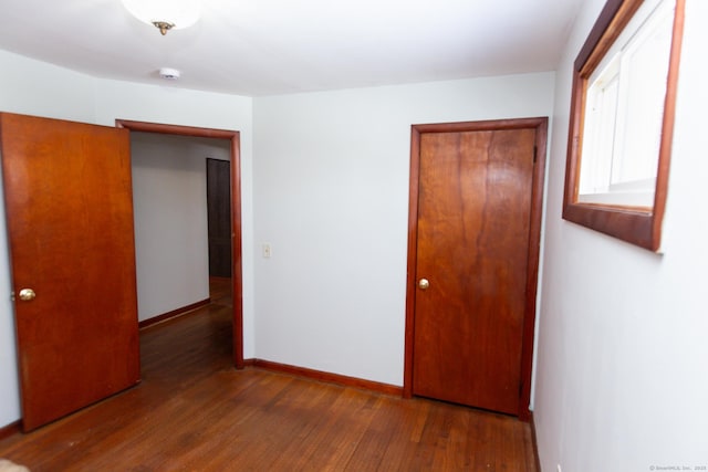 unfurnished bedroom with dark hardwood / wood-style floors and a closet