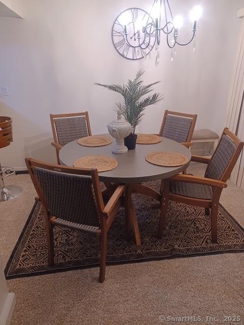 dining space with carpet flooring and a notable chandelier