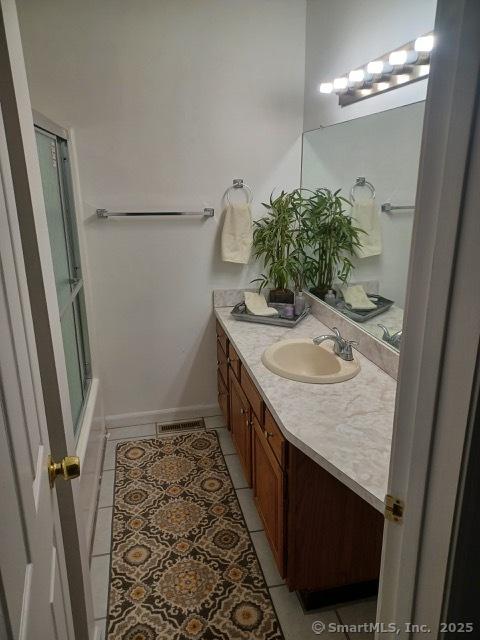 bathroom featuring vanity, combined bath / shower with glass door, and tile patterned flooring