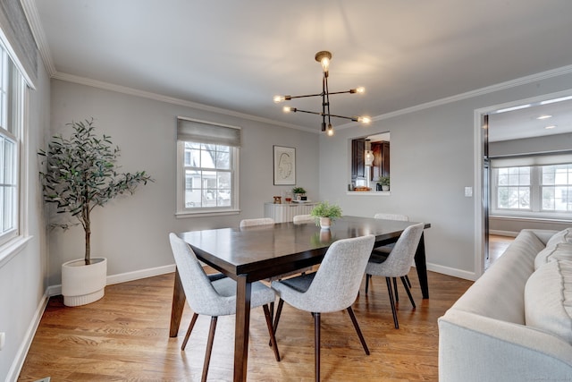 dining space featuring ornamental molding, a chandelier, and light hardwood / wood-style floors