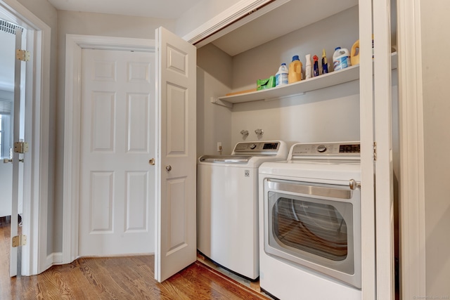 clothes washing area featuring separate washer and dryer and light hardwood / wood-style flooring