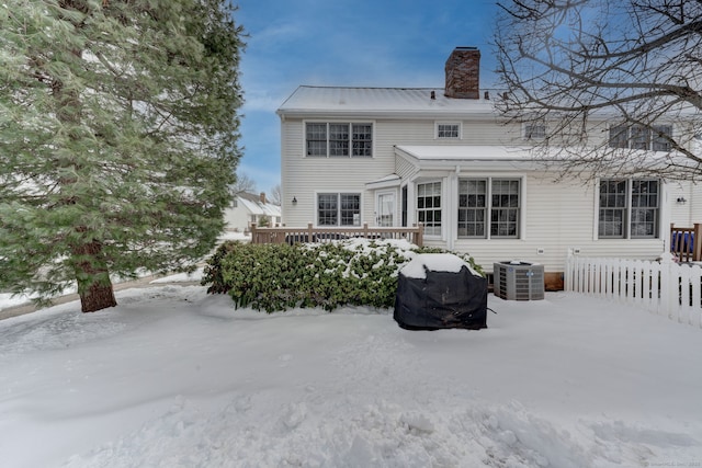 snow covered house with central AC unit and a deck