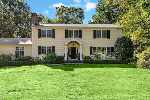 colonial home with a front yard and a chimney