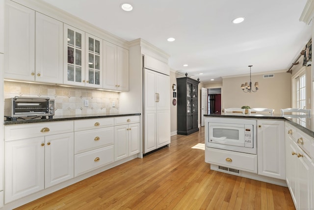 kitchen featuring glass insert cabinets, white microwave, white cabinetry, and visible vents