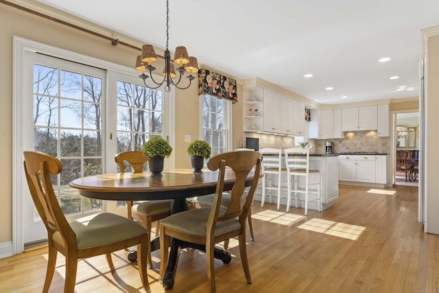 dining space with light wood-style floors, recessed lighting, crown molding, and an inviting chandelier