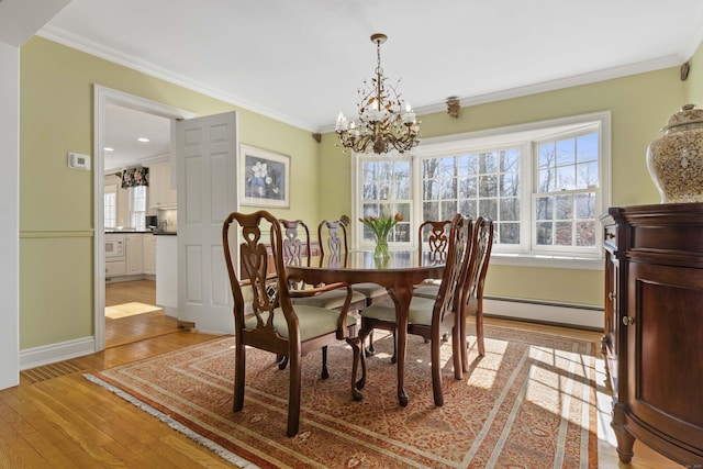 dining room featuring light wood-style flooring, a baseboard heating unit, a chandelier, and ornamental molding