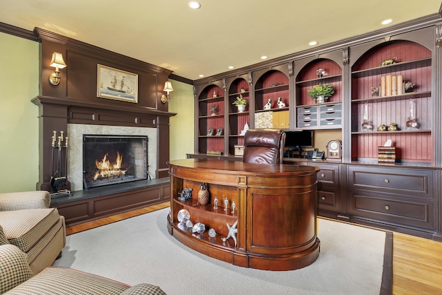 home office with light wood-style floors, recessed lighting, crown molding, and a premium fireplace