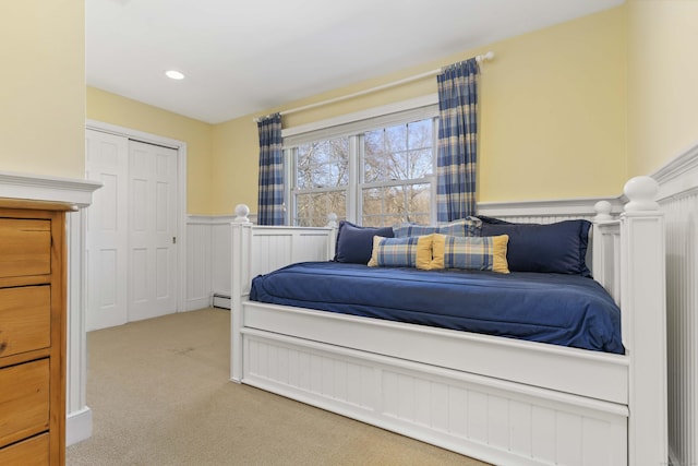 bedroom with a wainscoted wall, recessed lighting, a closet, light colored carpet, and a baseboard radiator