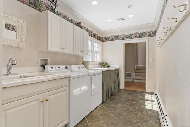 clothes washing area featuring washer and clothes dryer, cabinet space, baseboard heating, ornamental molding, and a sink