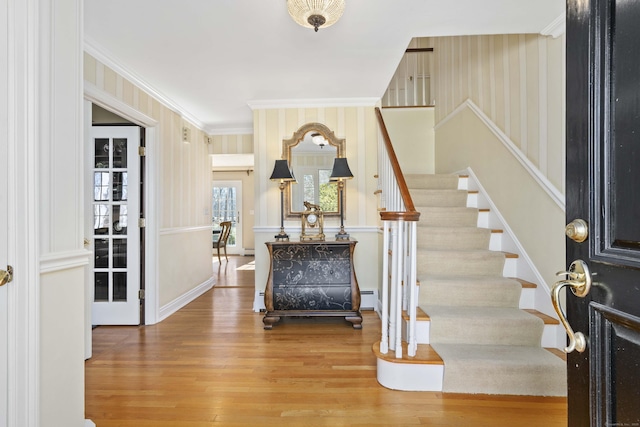 foyer entrance with stairs, a baseboard radiator, crown molding, and wood finished floors