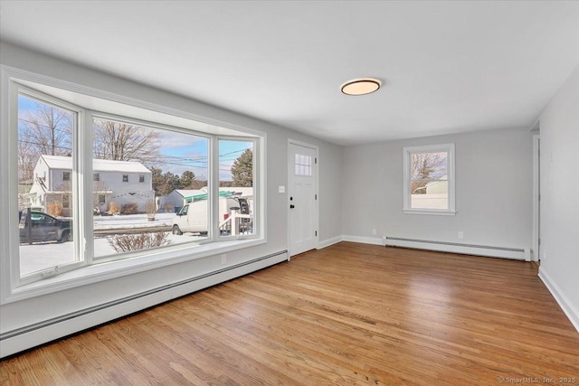 unfurnished room with light wood-type flooring and baseboard heating