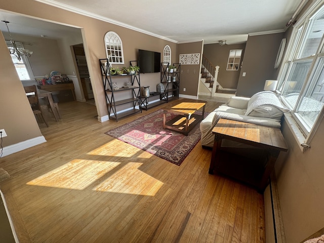 living room with wood-type flooring, ornamental molding, and a chandelier