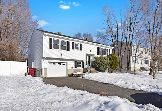 split foyer home featuring a chimney, fence, and driveway