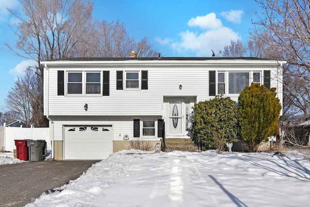 bi-level home with aphalt driveway, fence, and an attached garage