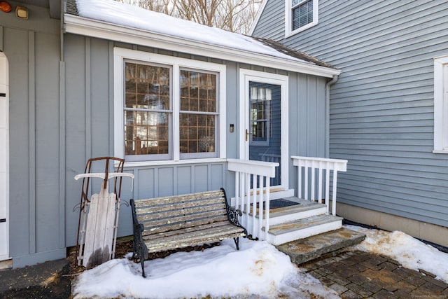 snow covered property entrance with board and batten siding