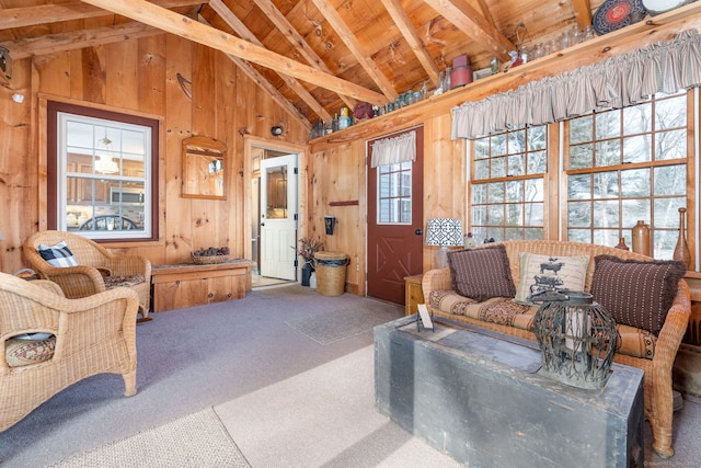 carpeted living area with lofted ceiling with beams, wood walls, and wooden ceiling