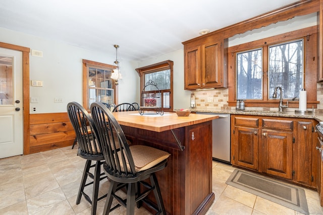 kitchen with brown cabinetry, dishwasher, a center island, pendant lighting, and wooden counters