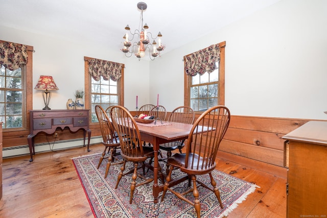 dining space with a baseboard heating unit, a notable chandelier, and light wood-style floors