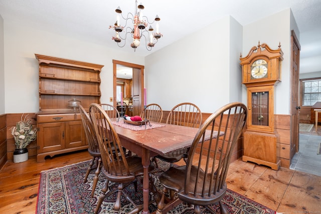 dining space featuring light wood-type flooring, wainscoting, and an inviting chandelier