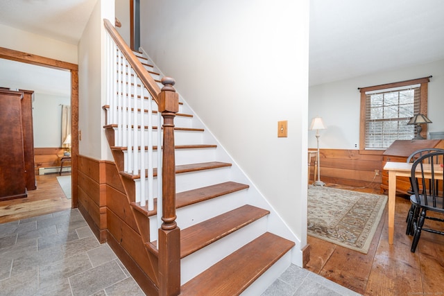 stairway featuring a baseboard radiator, wainscoting, wood walls, and wood finished floors