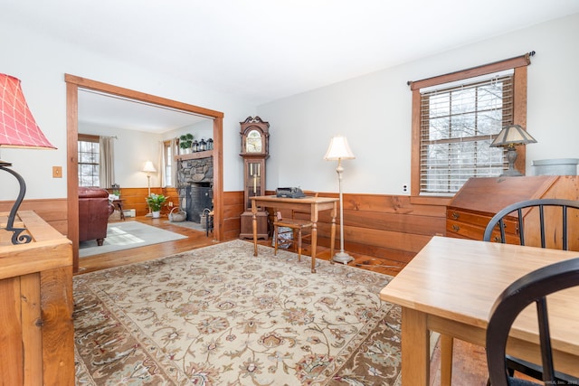 home office featuring a stone fireplace, wainscoting, wood finished floors, and wooden walls