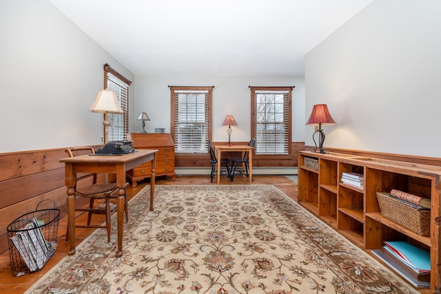 home office with a baseboard radiator, wainscoting, and wooden walls