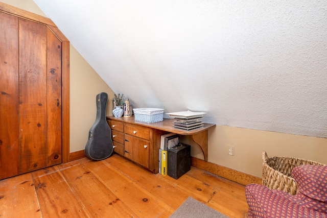 office area featuring vaulted ceiling, light wood finished floors, and baseboards