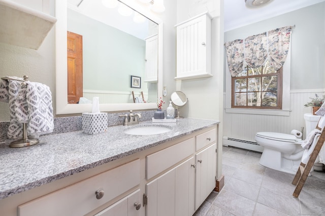 bathroom with toilet, a baseboard heating unit, vanity, wainscoting, and tile patterned floors