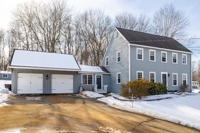 colonial house featuring aphalt driveway, board and batten siding, and an attached garage