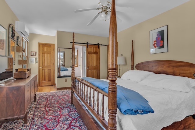 bedroom featuring dark hardwood / wood-style flooring, a wall mounted air conditioner, a barn door, and ceiling fan