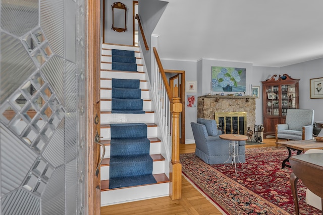 living room with hardwood / wood-style flooring, ornamental molding, and a stone fireplace