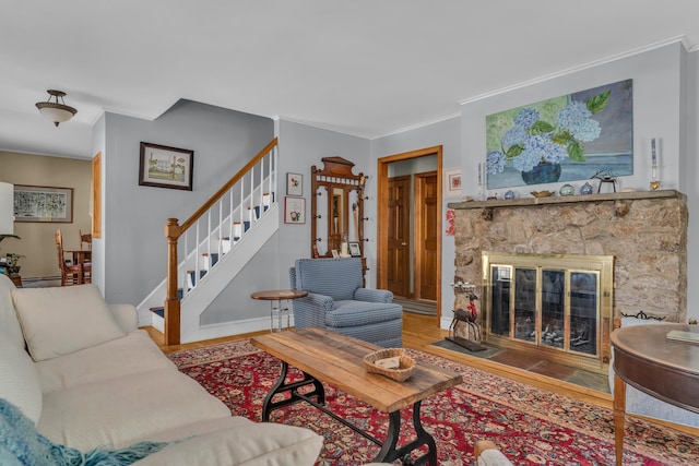 living room with hardwood / wood-style flooring, crown molding, a stone fireplace, and a baseboard heating unit