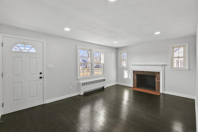 entryway with a brick fireplace, dark wood-type flooring, and radiator heating unit