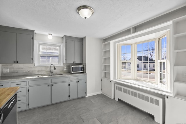 kitchen featuring radiator, sink, stainless steel appliances, a textured ceiling, and decorative backsplash