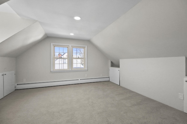 additional living space with vaulted ceiling, a baseboard heating unit, and light colored carpet