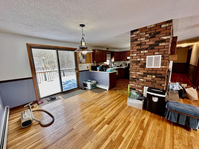 living room featuring baseboard heating, a textured ceiling, and light wood-type flooring