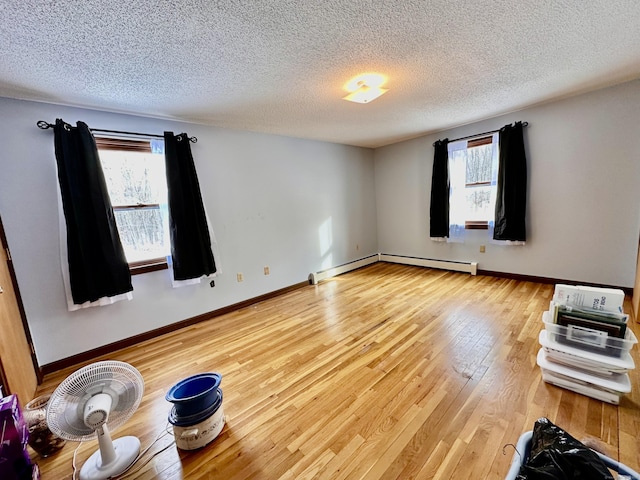 unfurnished room with a baseboard radiator, wood-type flooring, and a textured ceiling