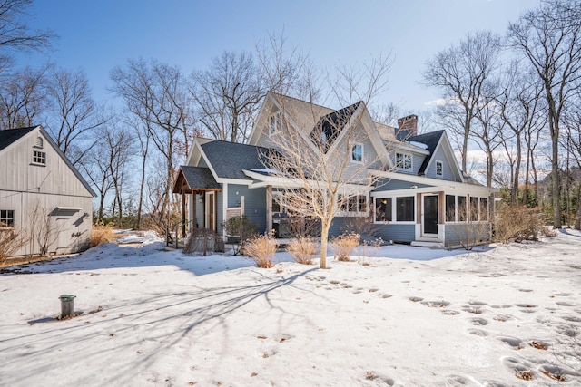 view of front of property featuring a chimney, an outdoor structure, and a sunroom