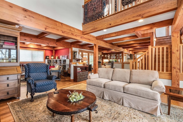 living room featuring beam ceiling, stairs, and wood finished floors