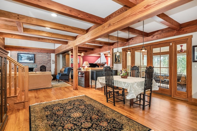 dining room with beamed ceiling, wood finished floors, and a fireplace