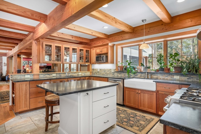 kitchen with beamed ceiling, a sink, stainless steel appliances, a peninsula, and decorative backsplash