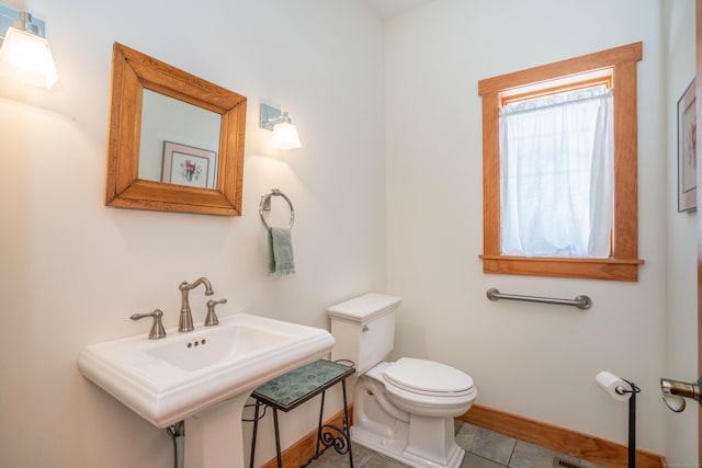 bathroom featuring tile patterned flooring, toilet, baseboards, and a sink