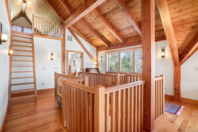 hall featuring wood finished floors, beamed ceiling, an upstairs landing, and visible vents