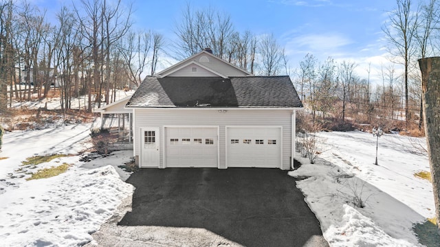 snow covered garage with a detached garage