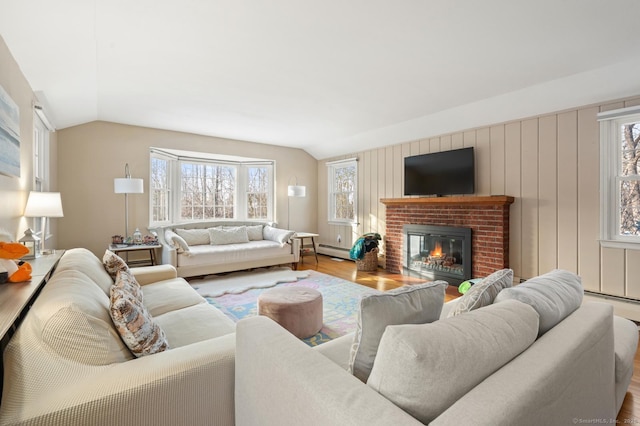 living area featuring a brick fireplace, a healthy amount of sunlight, vaulted ceiling, and baseboard heating