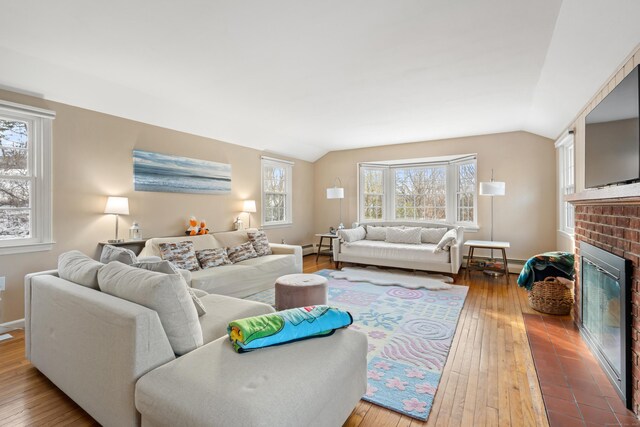 living room featuring hardwood / wood-style flooring, a fireplace, vaulted ceiling, and baseboard heating