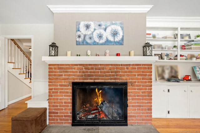 details featuring a brick fireplace, wood finished floors, and crown molding