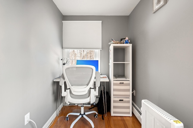 office space with a baseboard heating unit, baseboards, and wood finished floors