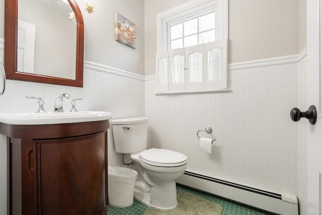 half bathroom featuring toilet, a wainscoted wall, a baseboard heating unit, and vanity