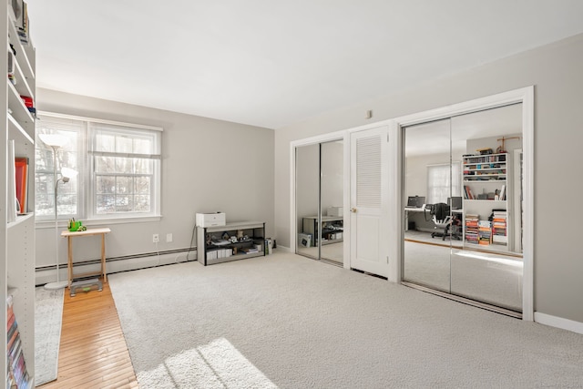 interior space featuring carpet floors, a baseboard radiator, baseboards, and wood finished floors